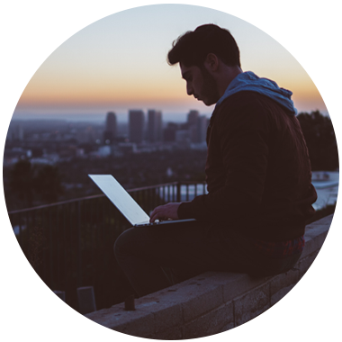 Person overlooking city on laptop at dusk