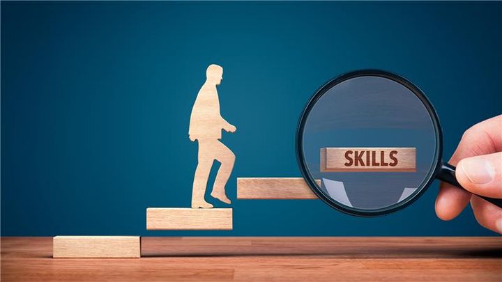 wooden cutout of a person walking up steps with "skills" under a magnifying glass