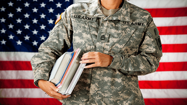 Soldier holding books in front of American flag