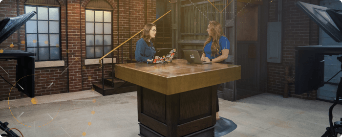 two women at host stand in studio set with laptops